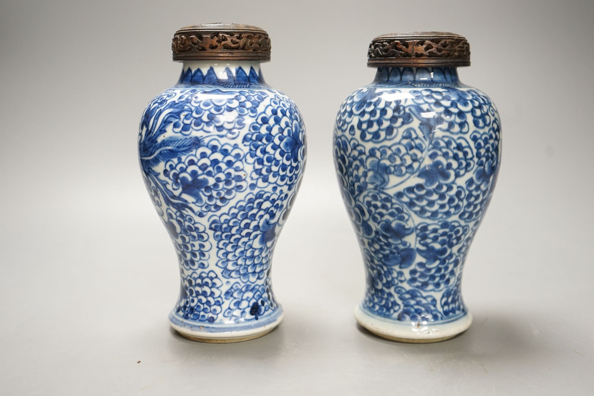A pair of Chinese blue and white 'phoenix' vases, Kangxi, associated wood covers, 19cm including covers